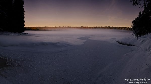 Nebel über dem zugefrorenen Oderteich, letztes Tageslicht, vom Sonnenuntergang orange gefärbt, Eiskristalle, Schneeverwehungen, Harz, Torfhaus, Deutschland