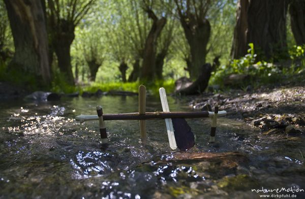 kleines Wasserrad aus Stöckchen und Eisstielen in einem Bach, im Hintergrund Kopffweiden, Naturschutzgebiet Unstruttal, Nägelstedt (Unstrut), Deutschland