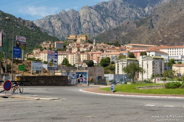 Kreisverkehr und Blick auf die Altstadt von Corte, dahinter Berge des Tavignano-Tals, Korsika, Frankreich
