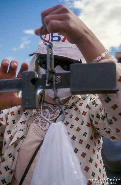 Verkäuferin mit Waage, mit Base-Cap, Sonnenbrille und Mundschutz, wiegt gerade eine Einkauftüte ab, Markt von Chowd, Chowd, Mongolei